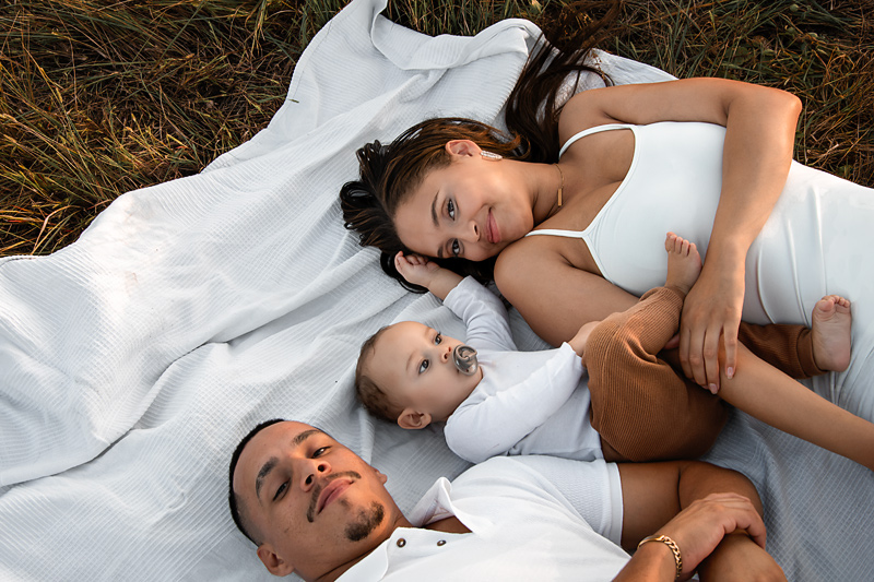 Familienfotografie im Feld – Babyjunge mit Eltern bei Sonnenuntergang und Golden Hour im Sommer in Berlin