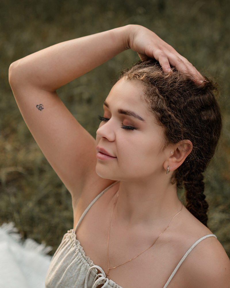 Junge Frau mit geschlossenen Augen bei einem ruhigen Moment im Outdoor-Fotoshooting
